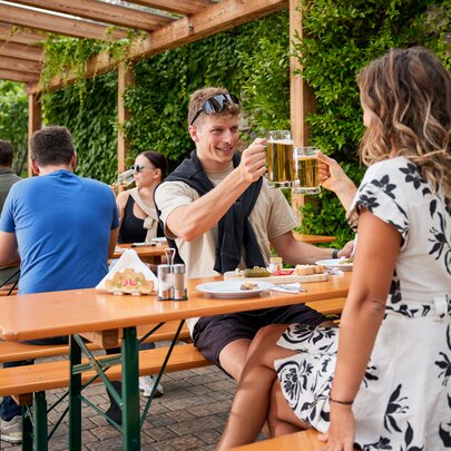 Several people enjoy Marende and beer at the Guggerhof on the classic beer garden table sets.